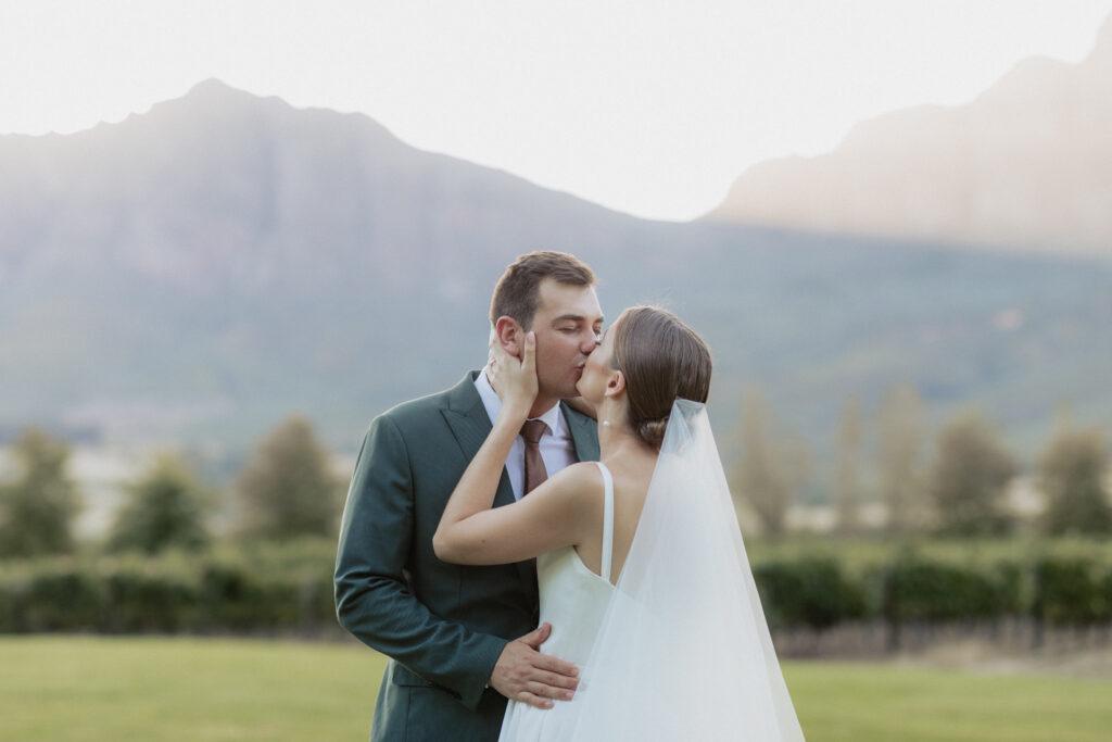 Wedding couple kissing with sunlit Tulbagh mountain behind them