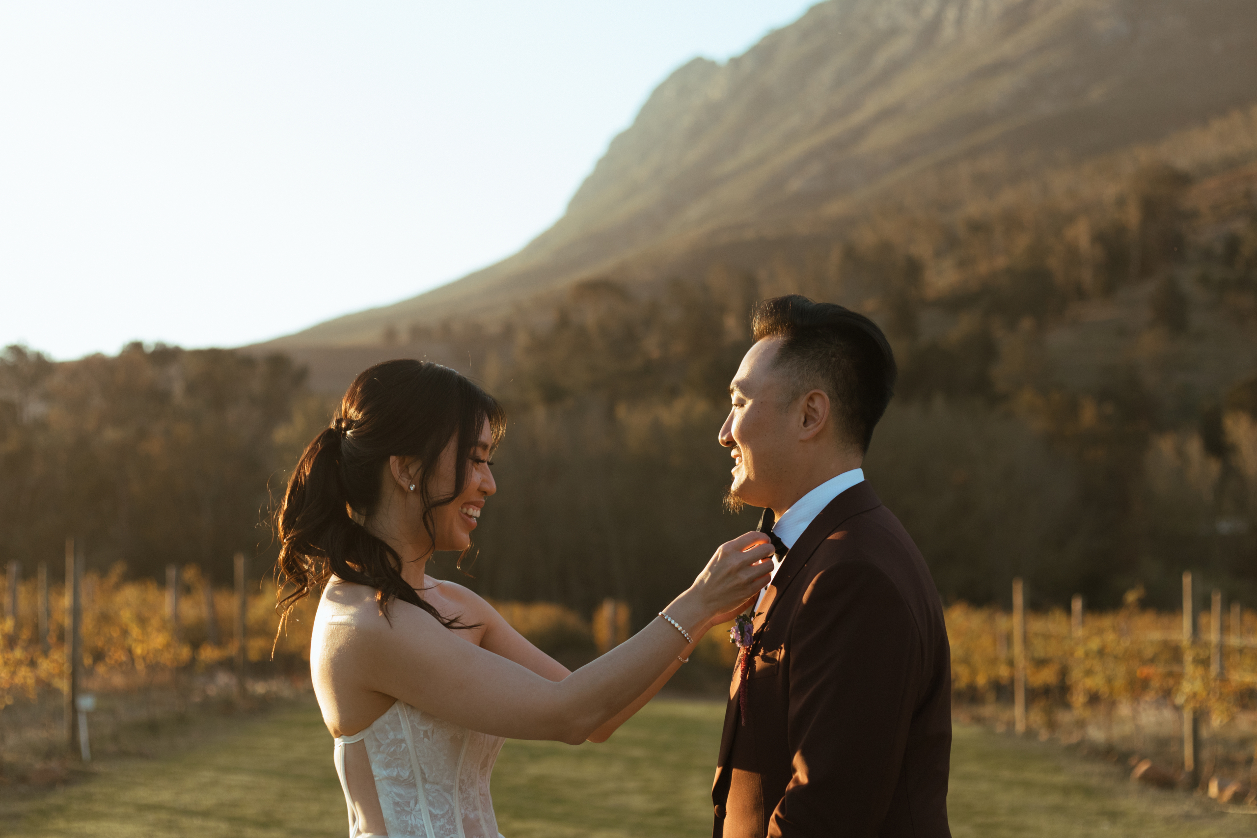 Bride straightening grooms bow tie during golden hour