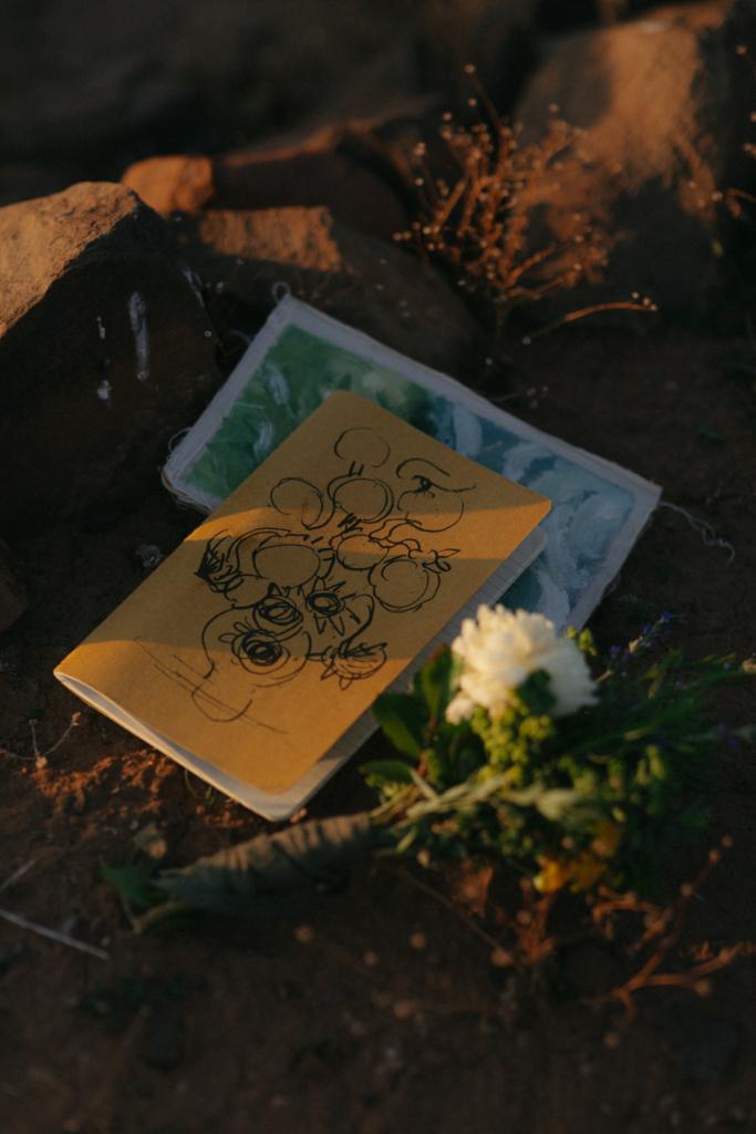 Bridal couple's artistic vow books and bouquet on the Karoo ground.