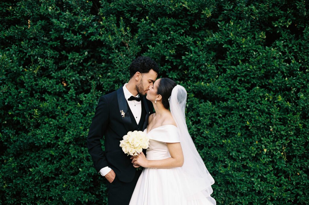 Wedding photograph on film of a couple kissing with foliage in the background
