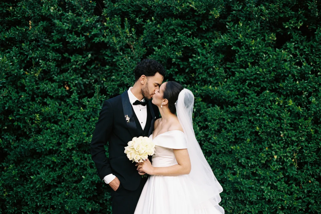 Wedding photograph on film of a couple kissing with foliage in the background