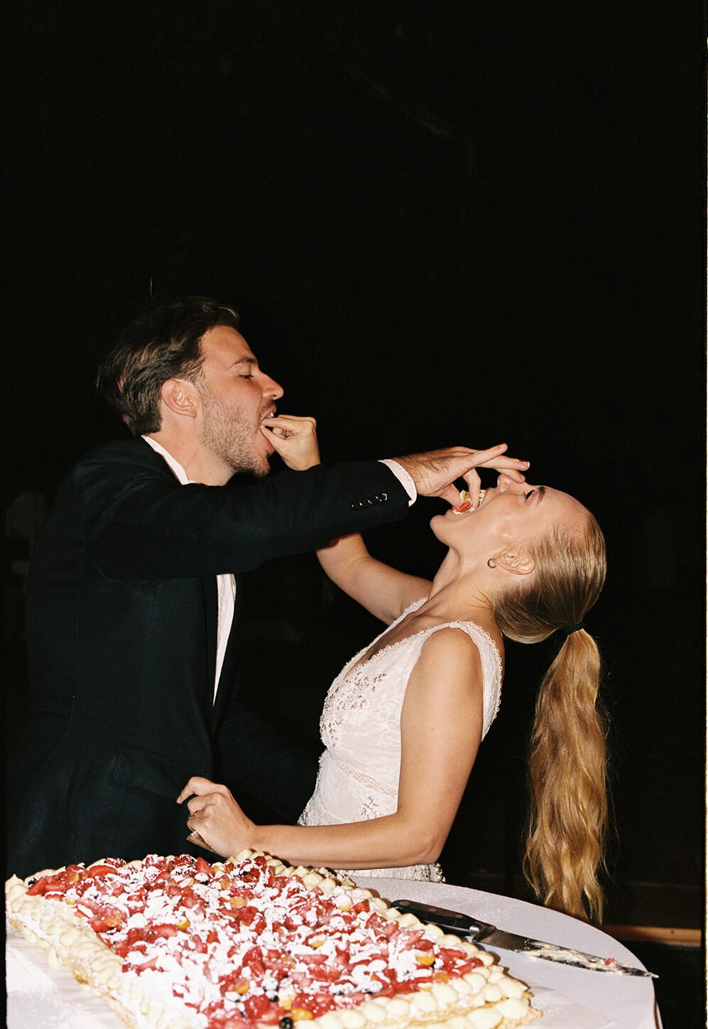 Fun film photography of a wedding couple eating their wedding cake