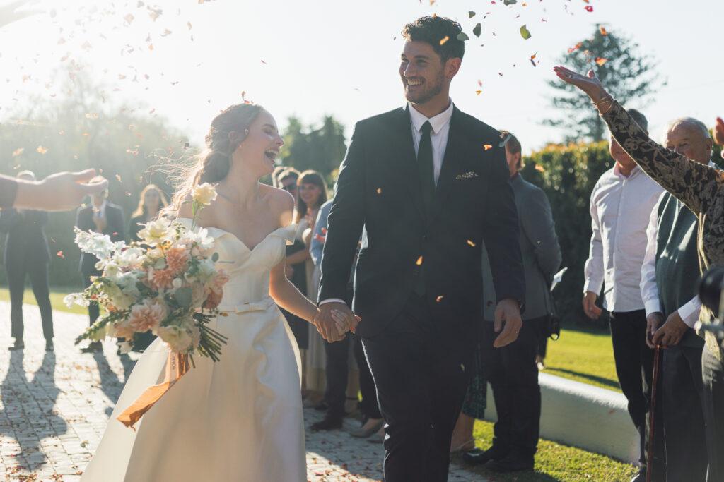 Wedding couple laughing while getting confetti thrown at them