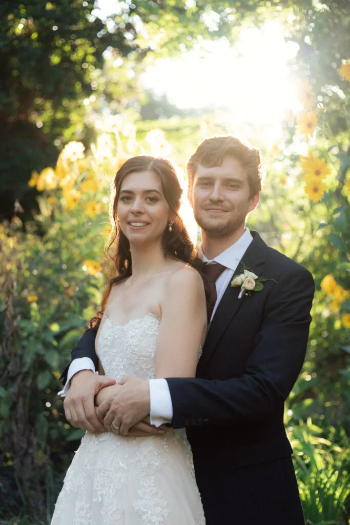 Wedding photography of a backlit wedding couple with foliage behind them.