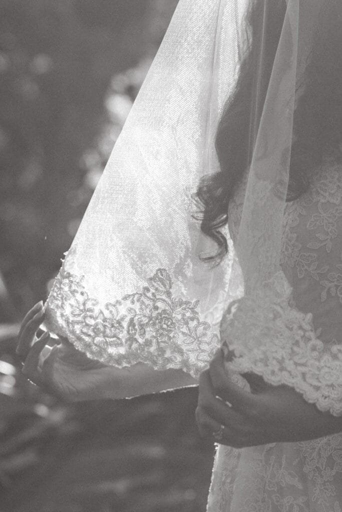 Black and white close up of a bride's veil in her hands