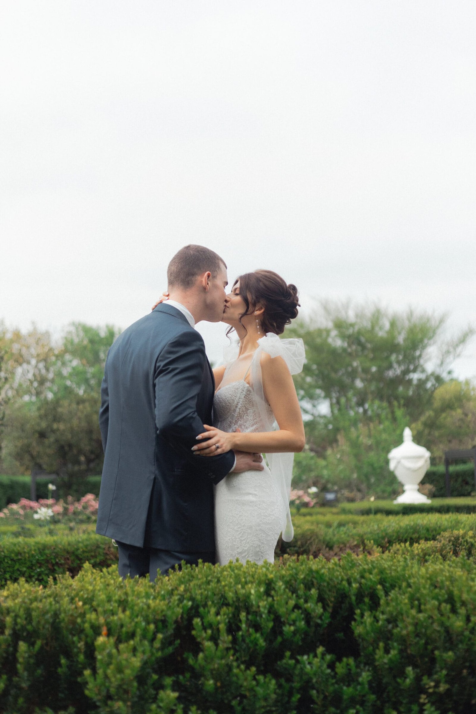 Wedding couple kissing in green maze like garden