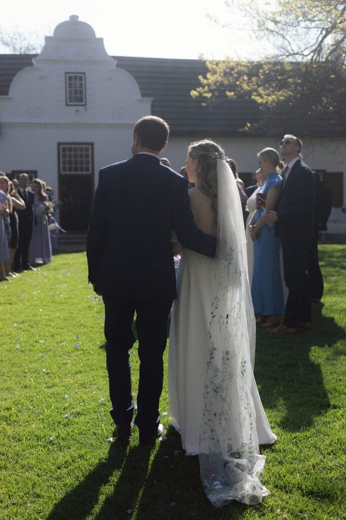 Bride and groom walking towards the manor during their wedding at Montpellier.