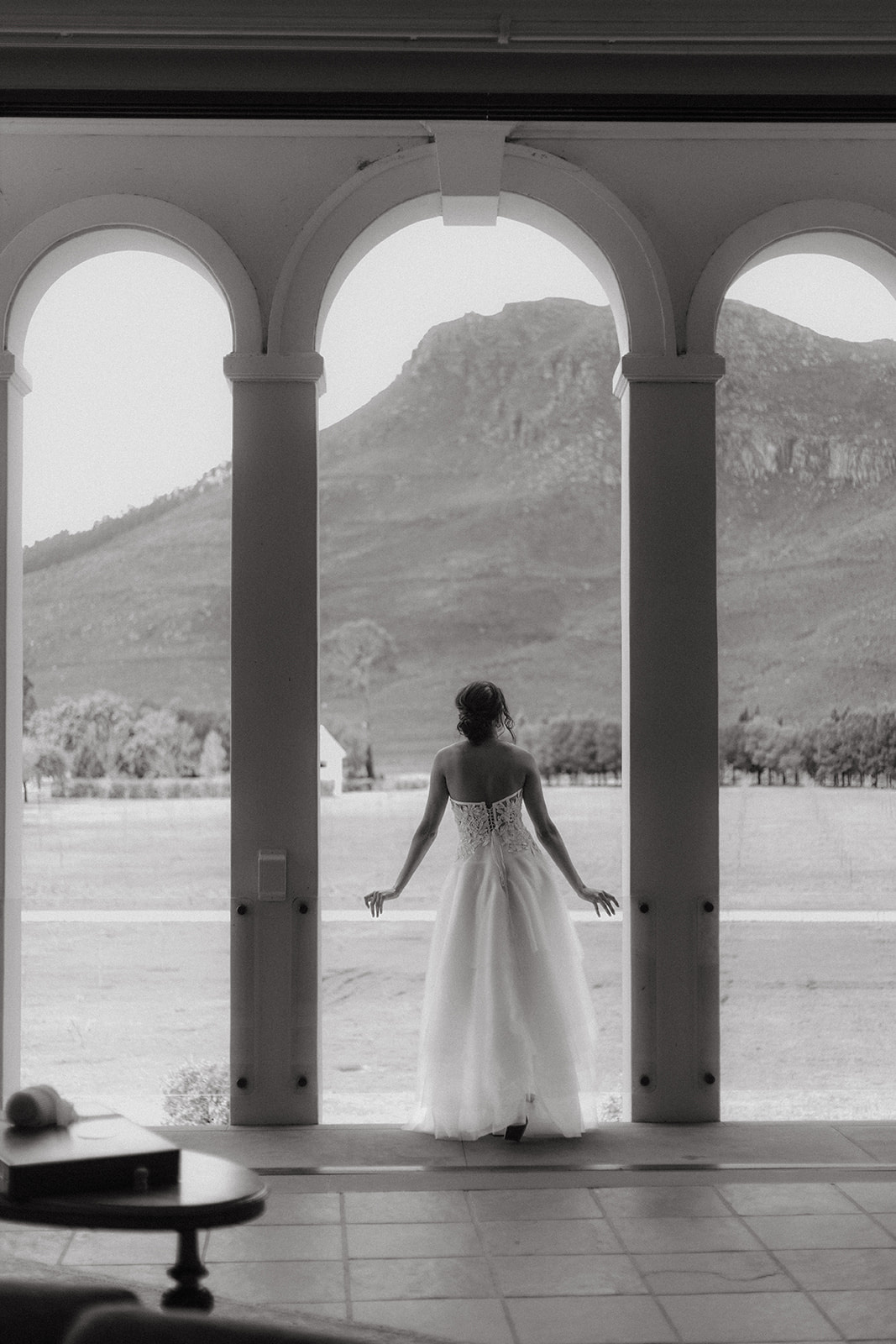 Black and white of a bride in La Roche's manor house looking towards the mountains.