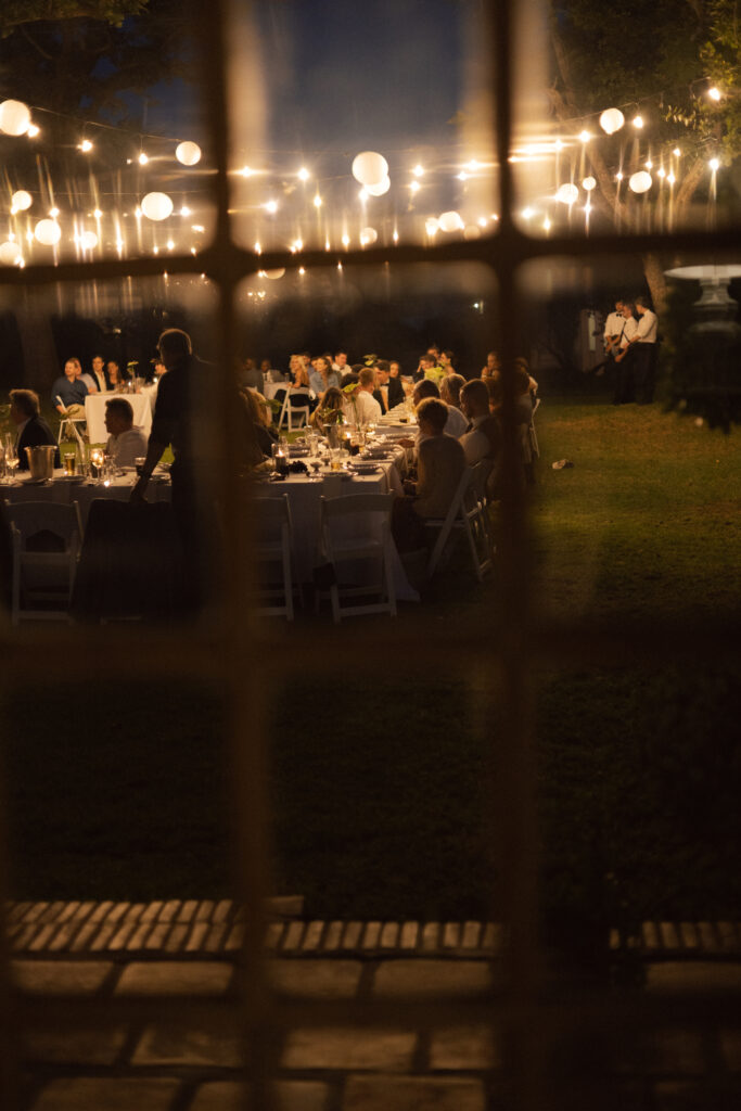 View of a wedding reception through a window with framed panes, used artfully to imply wedding photography packages.