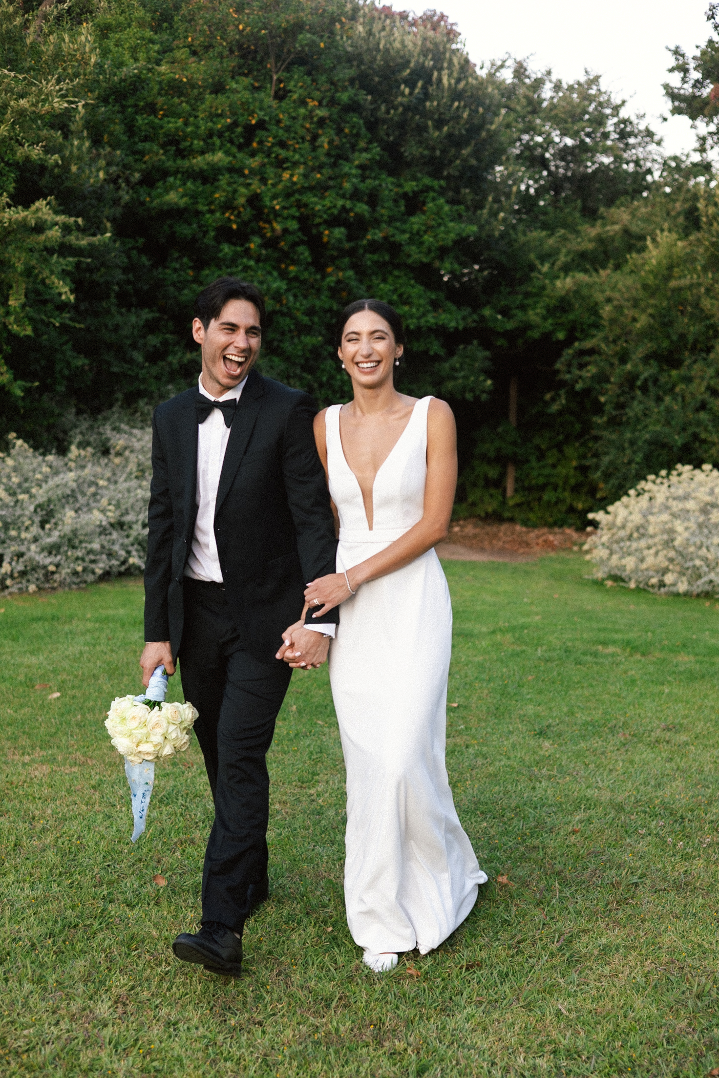 Wedding couple walking hand in hand laughing