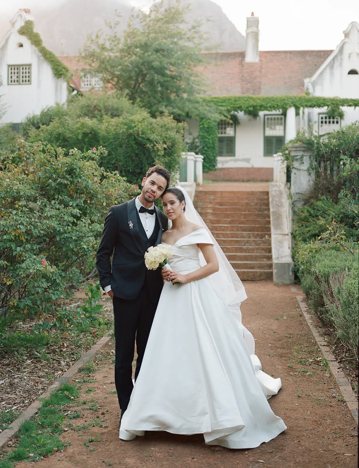 A wedding couple shot on film outside a colonial house