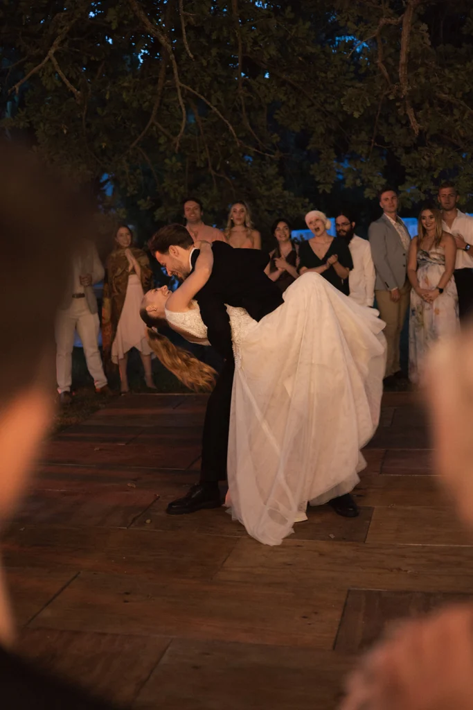 Wedding photography of a couple dancing. The groom is dipping the bride and their friends are surrounding them.
