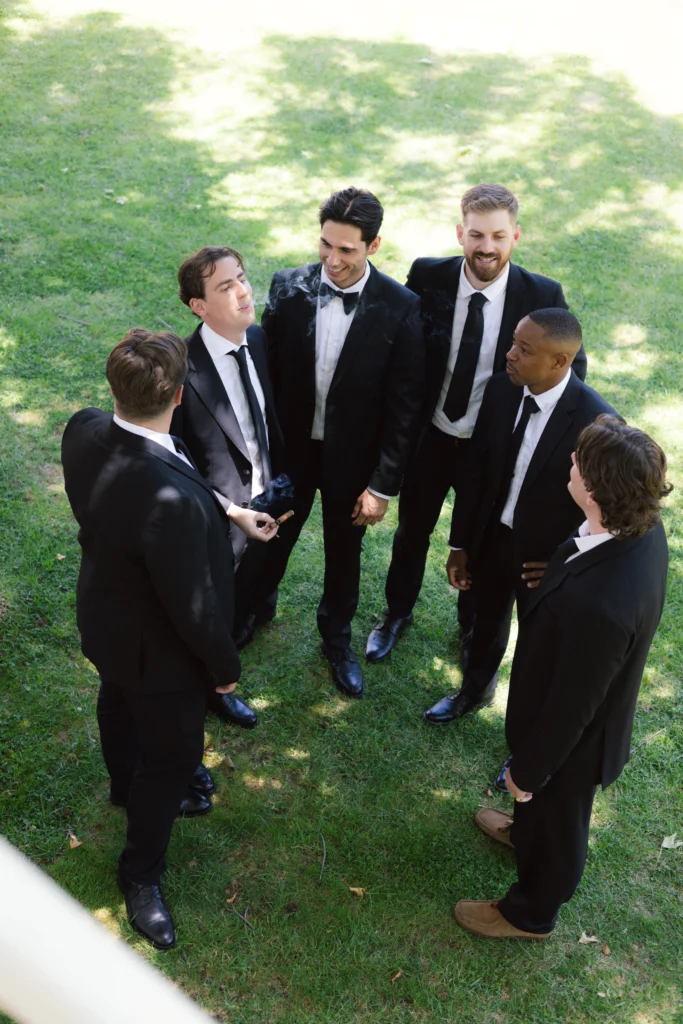 documentary-styled wedding image of groomsmen smoking together