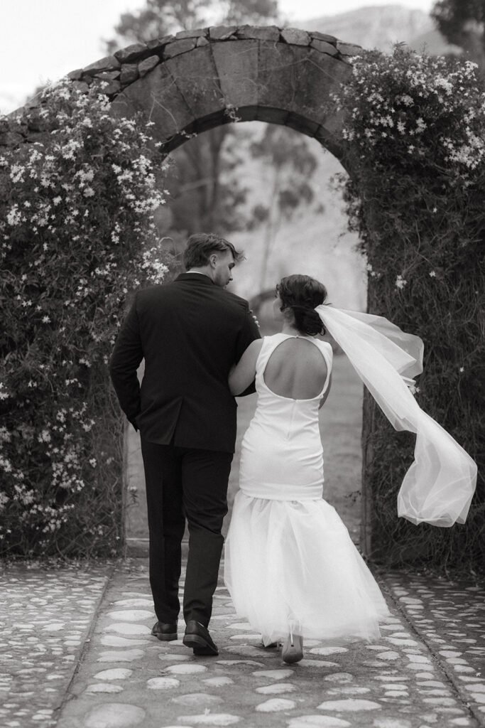 Candid Wedding photography shot of a couple walking through an archway