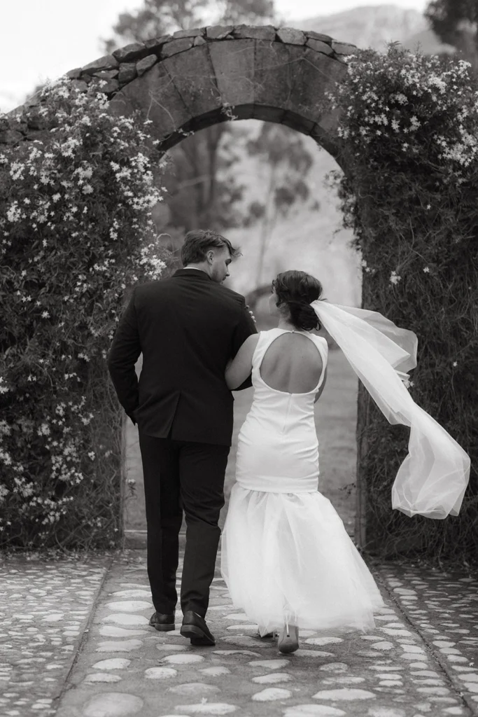 Candid Wedding photography shot of a couple walking through an archway