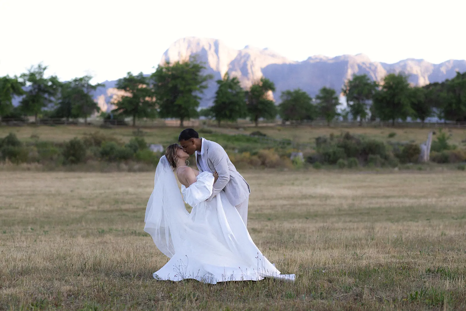 Wedding couple kissing with the Franschhoek mountains in the background.