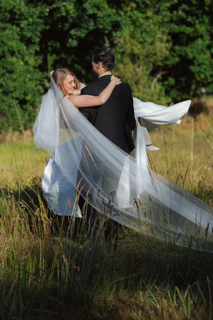 Wedding photo of a groom carrying his bride.
