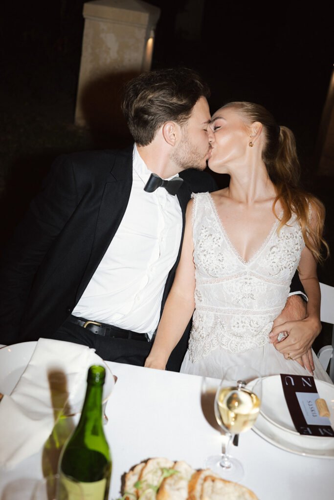 Wedding image of a couple kissing at their dinner table