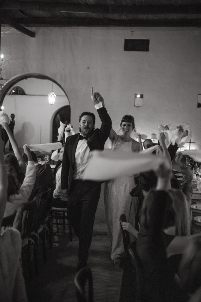 Wedding couple walking into their reception area to waving napkins